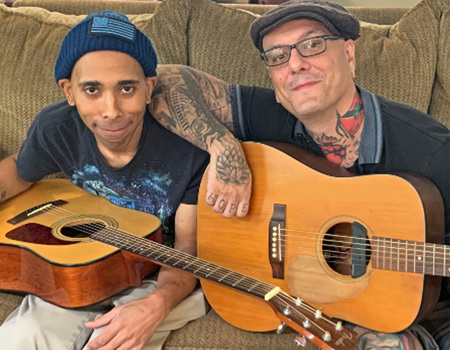Wounded warrior Marquise Morris sits on a couch holding a guitar during a music therapy session at home, offered through WWP’s Independence Program.