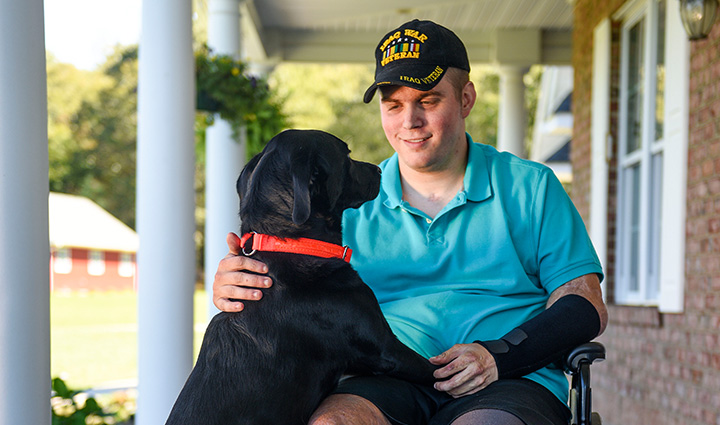 Wounded warrior Jason Ehrhart sitting in a wheelchair with his service dog.