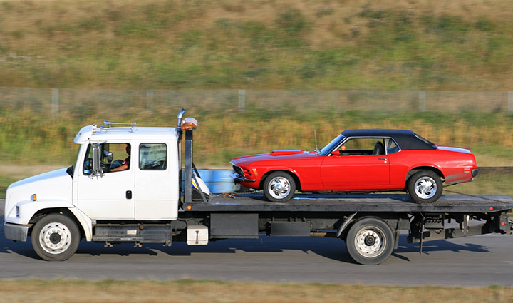 A red sports car being towed by a tow truck.