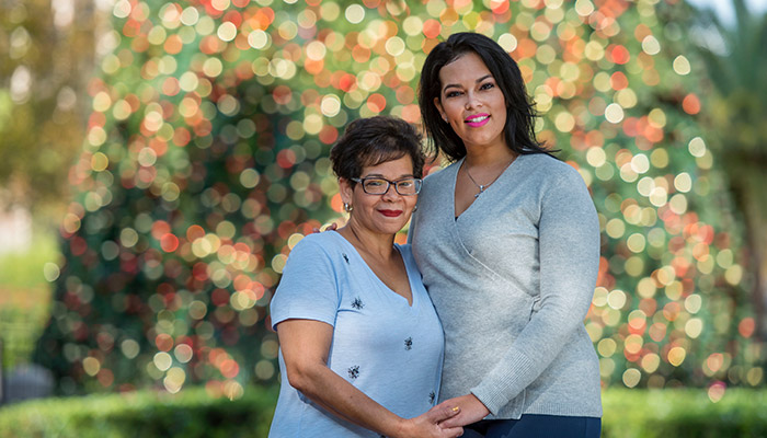 Wounded warrior Yomari Cruz and her mother posing in front of a Christmas tree while holding hands.