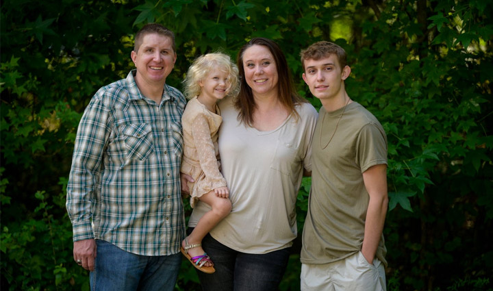 Wounded warrior Bobby Woods stands outside and poses for a photo with his wife, Sarah, and their children.