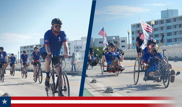 WWP Alumni ride road and adaptive bikes together along a sunny street with some carrying the American flag on their bikes.