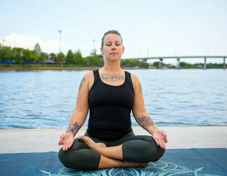 Wounded Warrior Jessica Coulter sitting outside doing a yoga pose and meditating.