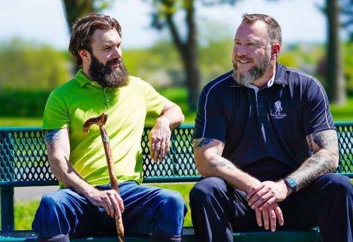Warriors Andrew Carpenter and Anthony Craiden sit outside on a bench together talking with each other.