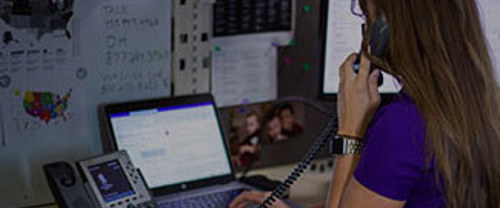 Woman sitting in office in front of a laptop screen while talking on a telephone