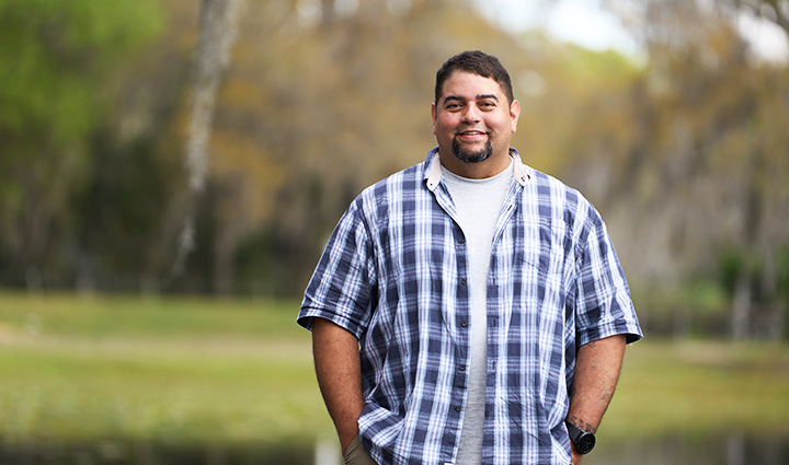 Wounded warrior Tim Aponte smiles while standing outdoors and putting his hands in his pockets.