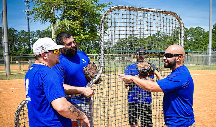 Warrior Carlos De Leon stands on a baseball field with three fellow warriors.