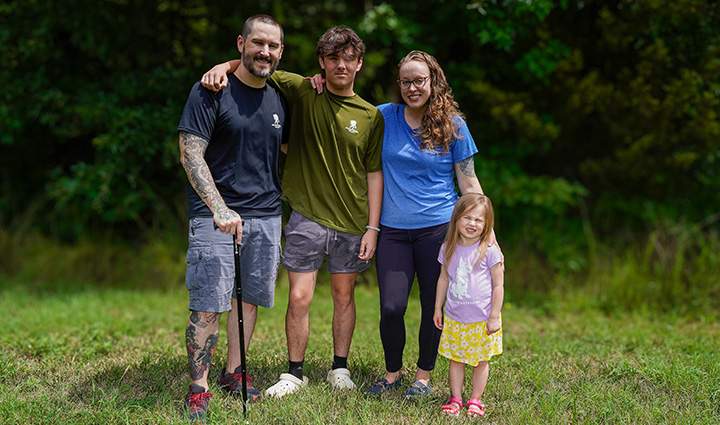 Warrior Xander Hernandez and his family standing on grass with green foliage background.