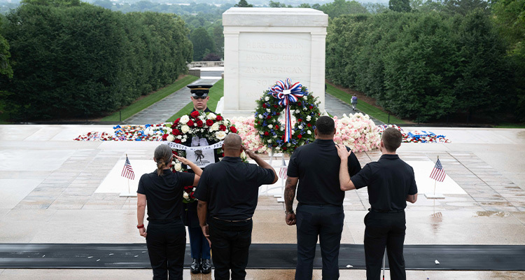 Four people salute during a wreath-laying ceremony at a tomb_750x400