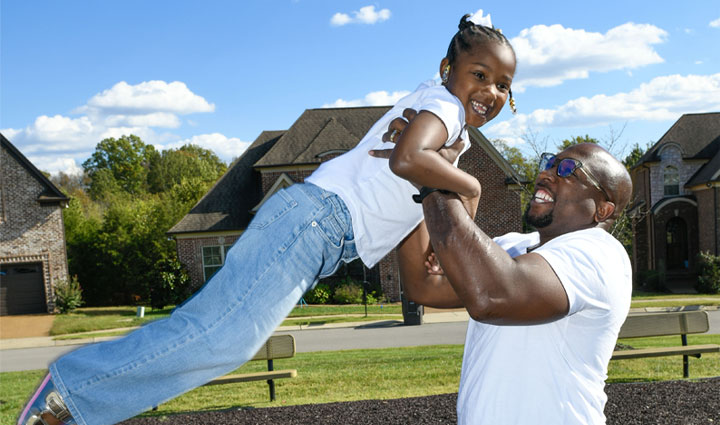 Warrior Melvin Gatewood smiling and picking up his daughter.