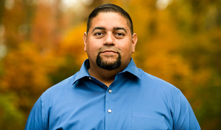 Wounded warrior Tim Aponte smiling and wearing a blue shirt.