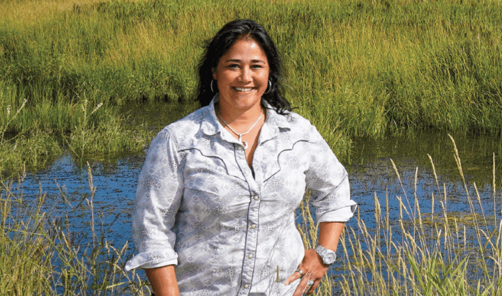 WWP warrior Tina Waggener is standing in a field with a pond in the background.