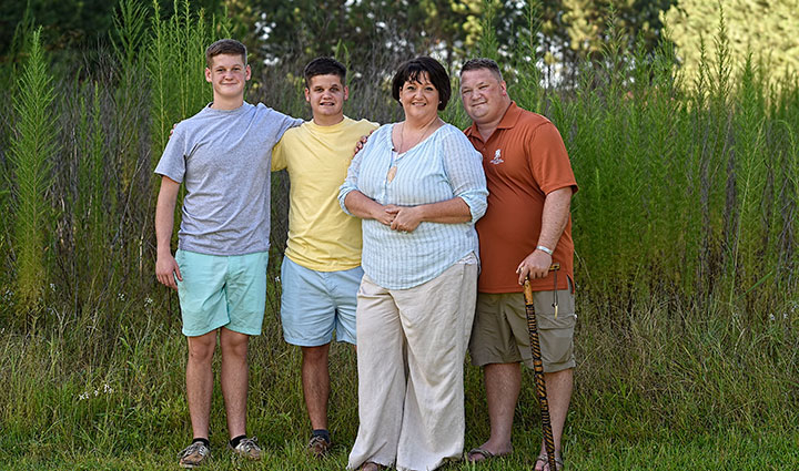 Warrior Tom Marcum stands next to his wife and two sons outside.