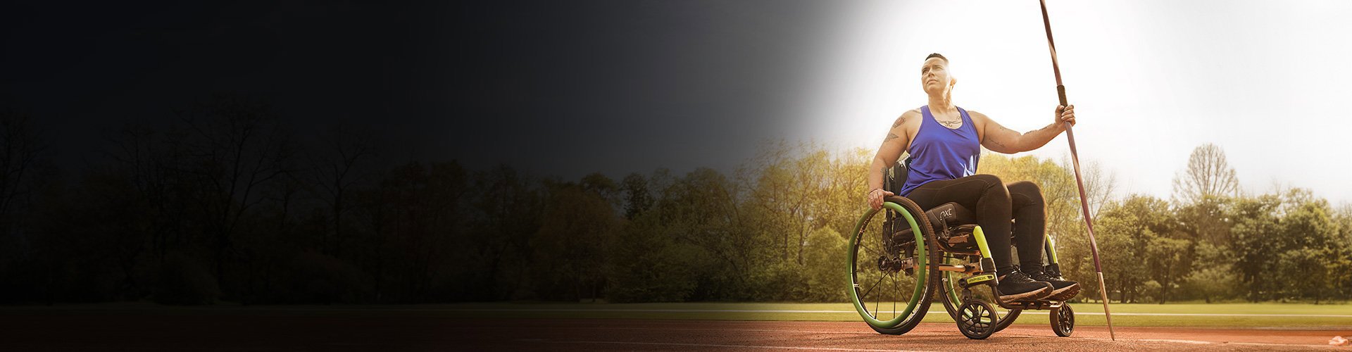 Wounded warrior Beth King sitting in a wheelchair and holding a javelin on a track field.