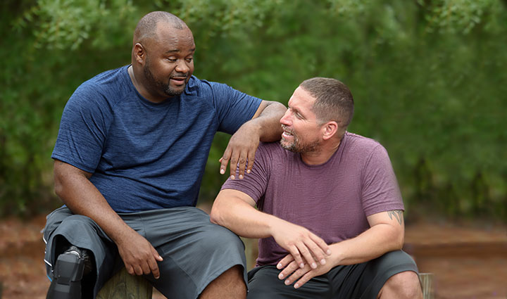 Warrior Chris Gordon sits next to fellow wounded Warrior Manny Colon while talking.
