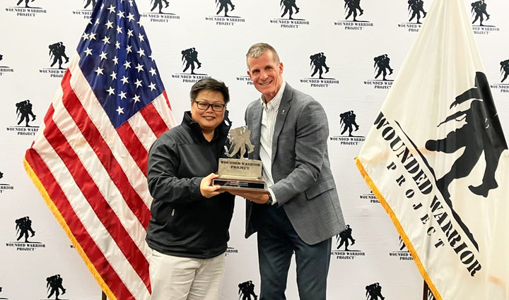 WWP teammate receives award in front of American flag and WWP flag.
