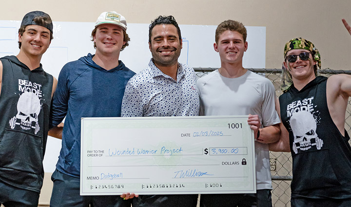Wounded warrior Sal Gonzalez stands with four young men holding a large check to WWP. 