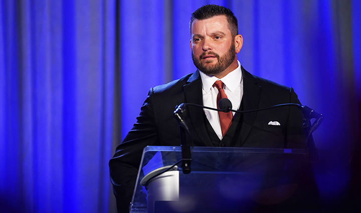Wounded warrior Sean Karpf dressed in formal attire speaks to the audience during the Courage Awards and Benefit Dinner.