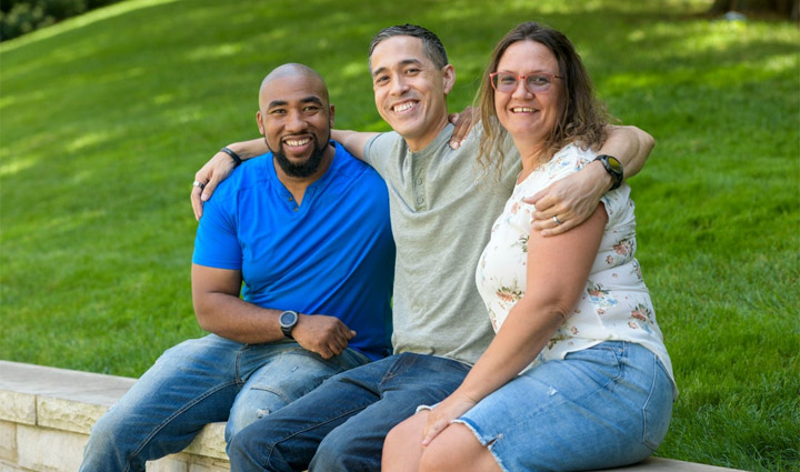 Wounded warriors Michael Powell, Sergio Alfaro, and Nicole Shorter sit atop a brick wall and smile for a group photo.