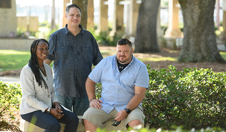 Wounded warriors Danielle Green and Jake Norotsky sit on a bench, accompanied by fellow warrior Jason Major standing beside them.