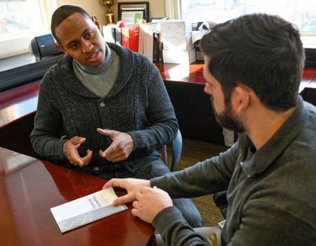 Wounded Warrior Tyshawn Jenkins sitting at a desk discussing Financial Wellness with an advisor.
