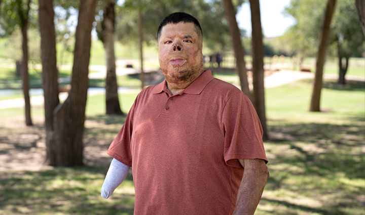Wounded warrior Anthony Villareal stands outside, wearing a red polo and smiling at the camera.
