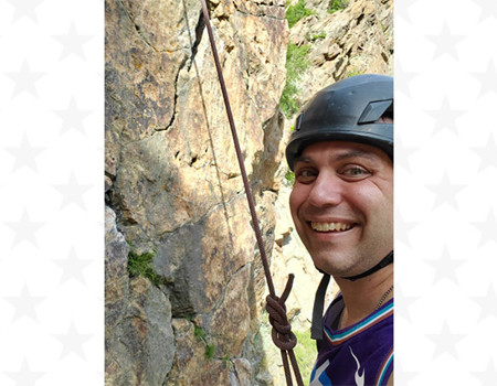 A close-up photo captures WWP warrior Michael Cumming mountain climbing, finding healing in the outdoors through WWP's PH&W program.